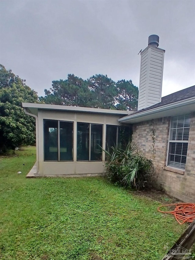 rear view of property featuring a sunroom and a yard