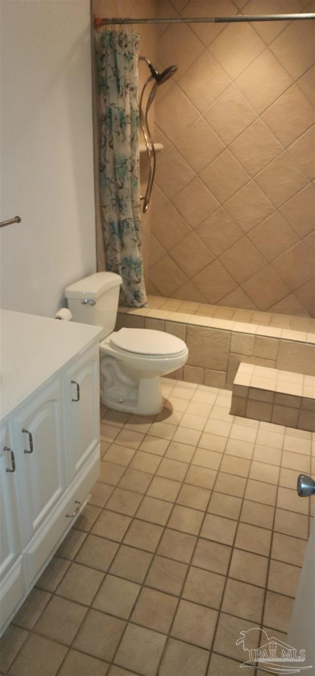 bathroom featuring walk in shower, vanity, toilet, and tile patterned flooring