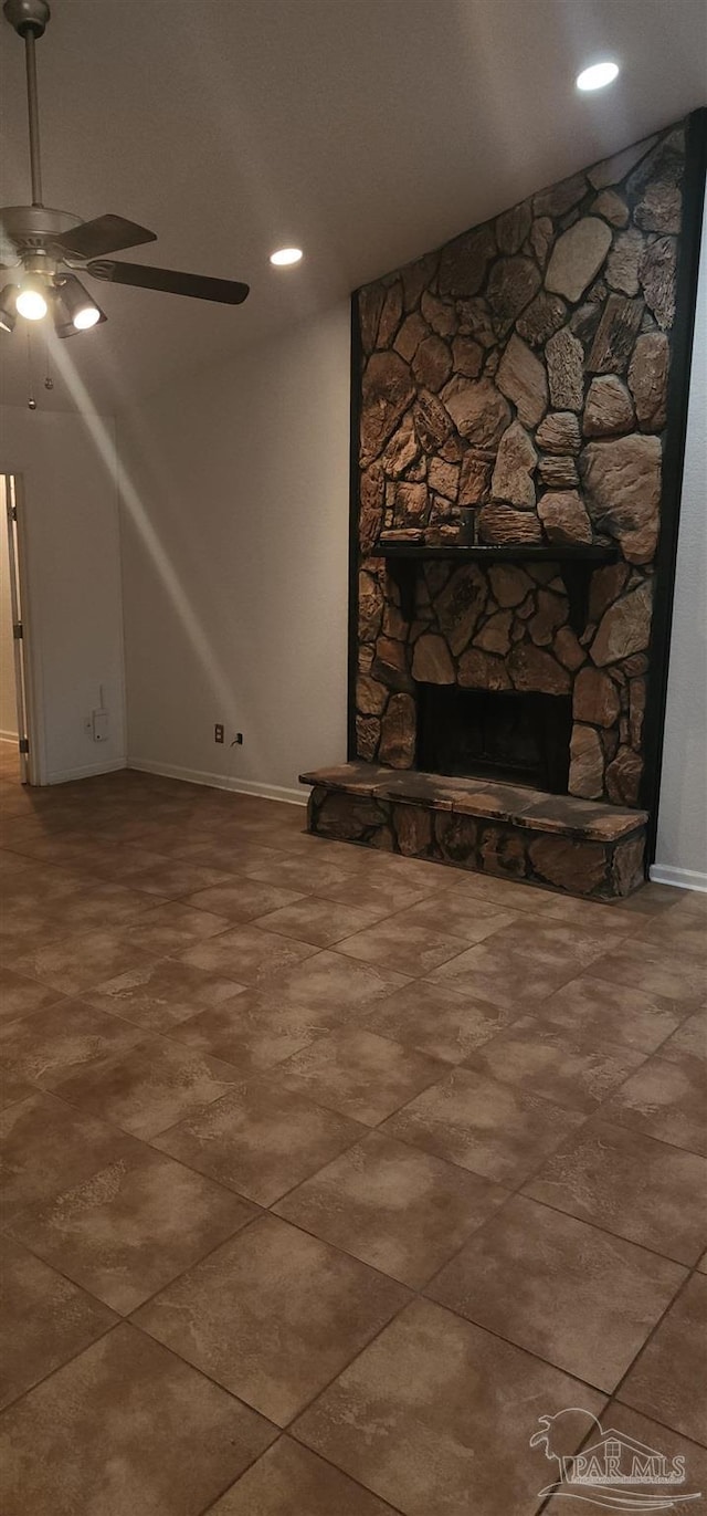 unfurnished living room with ceiling fan and a stone fireplace