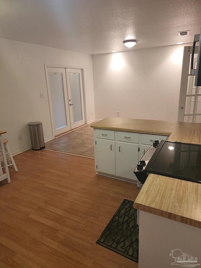 kitchen featuring light hardwood / wood-style flooring, range with electric cooktop, french doors, and a textured ceiling