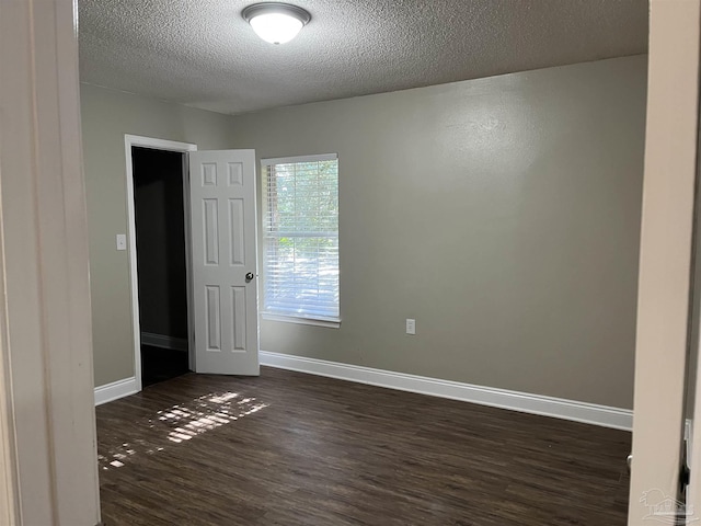 spare room featuring a textured ceiling and dark hardwood / wood-style floors