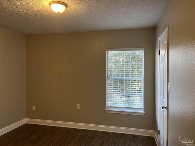 empty room with dark hardwood / wood-style floors and a textured ceiling