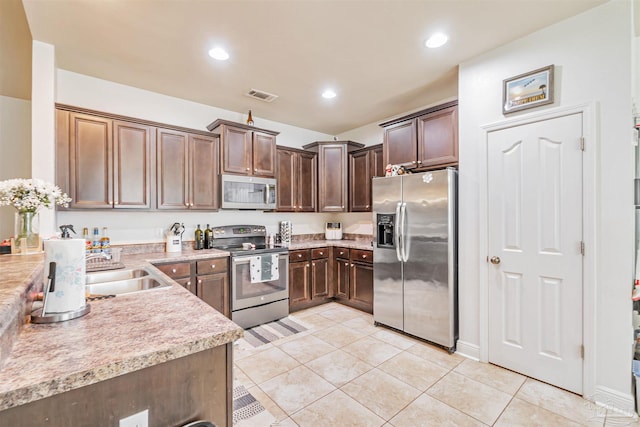 5811 Rustic Ridge Cir, Milton, FL 32570 - kitchen featuring appliances with stainless steel finishes, light tile patterned floors, light countertops, a sink, and dark brown cabinets