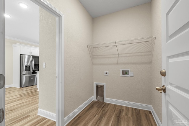clothes washing area featuring laundry area, hookup for an electric dryer, hookup for a washing machine, baseboards, and light wood-style flooring