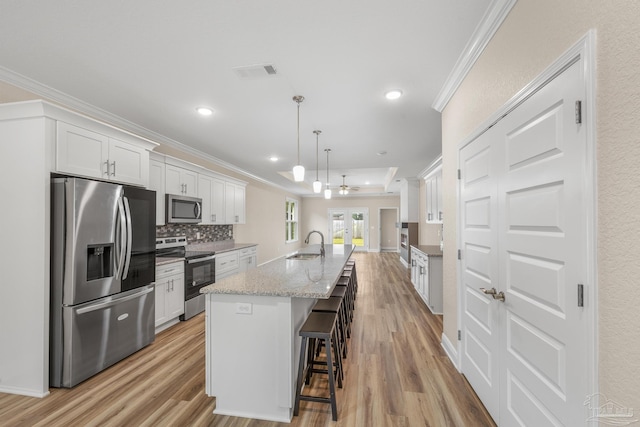 kitchen with light wood-type flooring, ornamental molding, a sink, and appliances with stainless steel finishes
