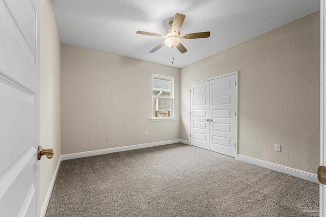unfurnished bedroom with ceiling fan, a closet, a textured wall, and carpet