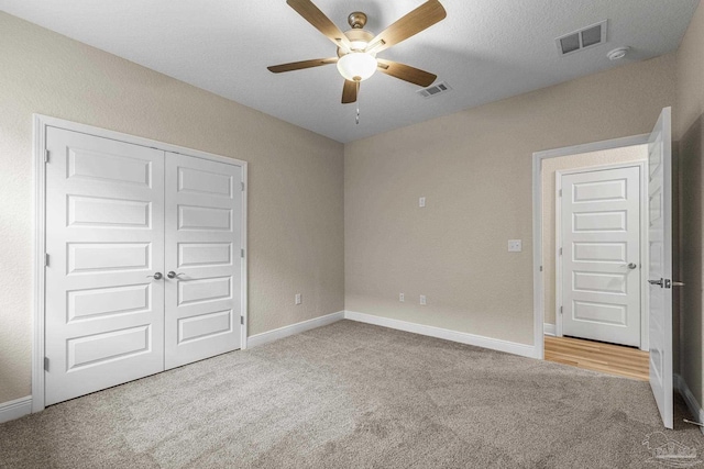 unfurnished bedroom with a closet, carpet, visible vents, and baseboards