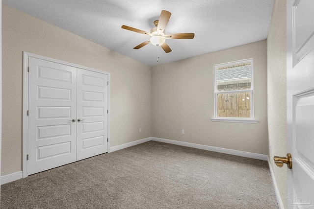 unfurnished bedroom featuring baseboards, carpet floors, ceiling fan, and a closet