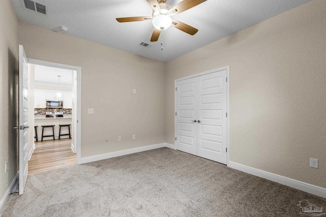 unfurnished bedroom with light colored carpet, ceiling fan, baseboards, and visible vents