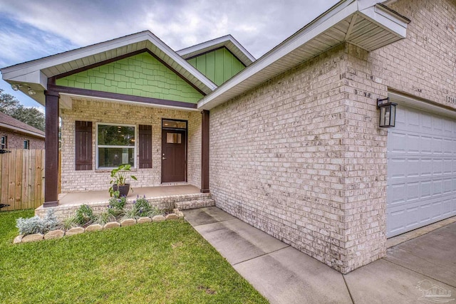 doorway to property featuring fence, a yard, a porch, brick siding, and a garage