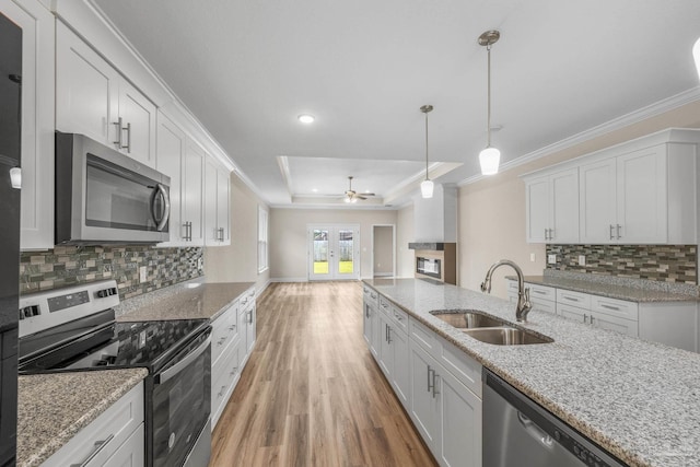kitchen with stainless steel appliances, a raised ceiling, a sink, light wood-type flooring, and crown molding