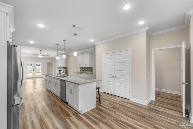 kitchen with a ceiling fan, a sink, light wood-type flooring, stainless steel appliances, and ornamental molding