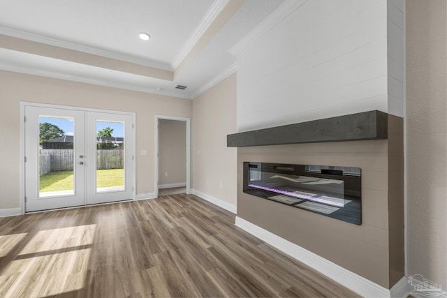 unfurnished living room with wood finished floors, french doors, a large fireplace, baseboards, and ornamental molding