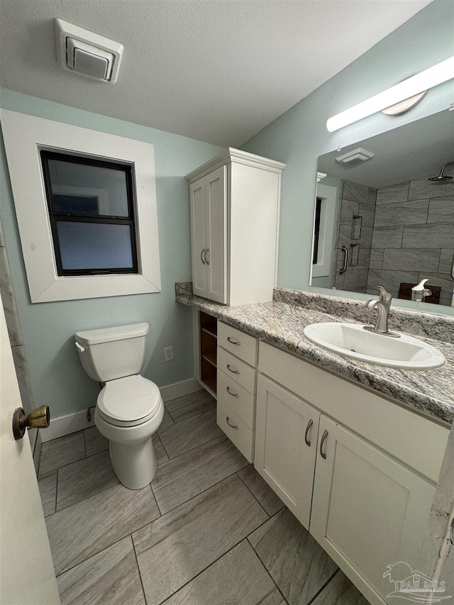 bathroom featuring a shower with door, vanity, a textured ceiling, and toilet