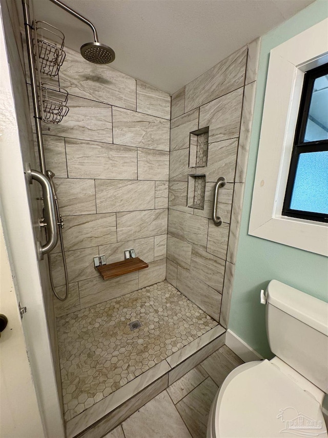 bathroom with a tile shower and toilet