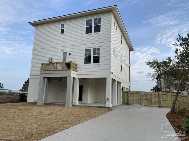 1557 Winding Shore Dr, Gulf Breeze, FL 32563 - rear view of house with a gate, concrete driveway, board and batten siding, and a balcony