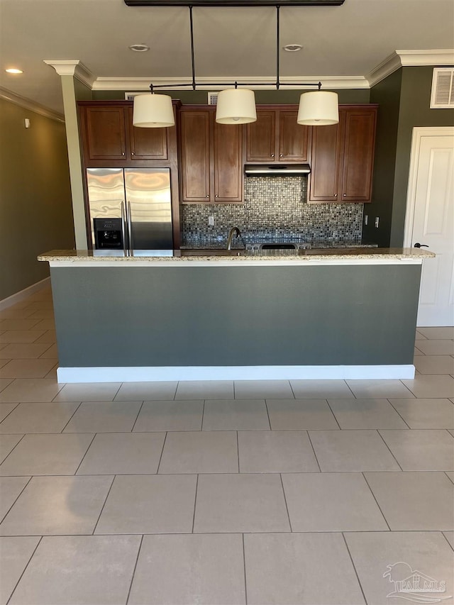 kitchen featuring crown molding, stainless steel fridge, a kitchen island with sink, and hanging light fixtures