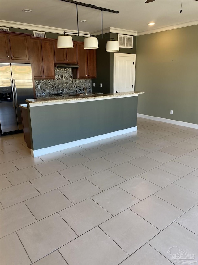 kitchen featuring pendant lighting, stainless steel fridge, a kitchen island with sink, and crown molding