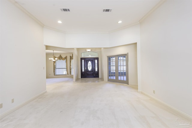 carpeted entrance foyer with crown molding, an inviting chandelier, and french doors