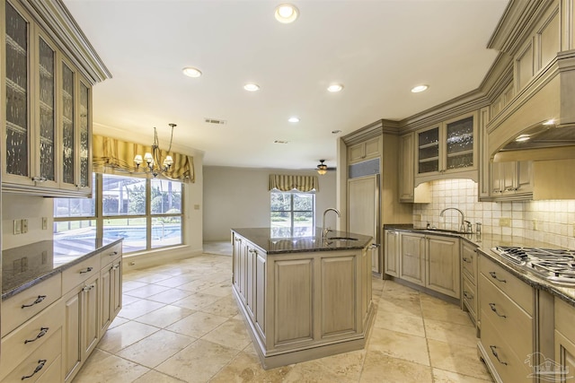 kitchen featuring stainless steel gas stovetop, a kitchen island with sink, sink, and decorative light fixtures