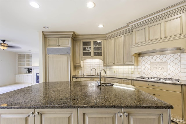 kitchen featuring paneled refrigerator, sink, and a center island with sink