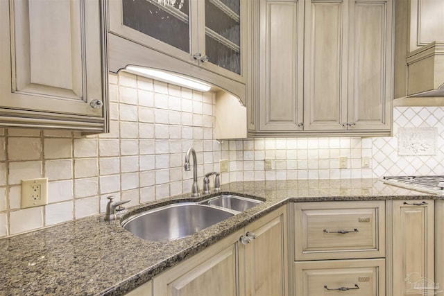 kitchen with dark stone countertops, sink, and backsplash