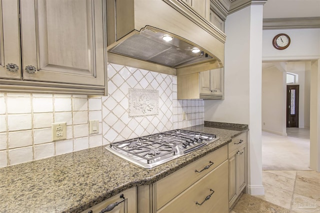 kitchen featuring premium range hood, ornamental molding, stainless steel gas cooktop, and dark stone counters