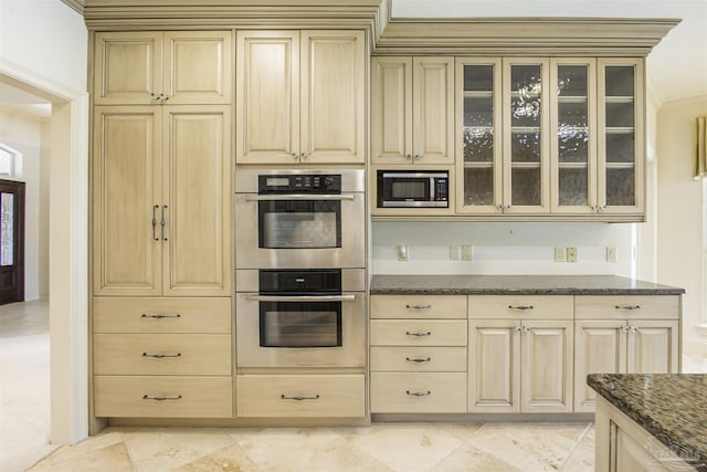 kitchen featuring appliances with stainless steel finishes, light brown cabinets, and dark stone counters