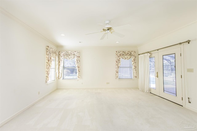 empty room with crown molding, light colored carpet, french doors, and ceiling fan