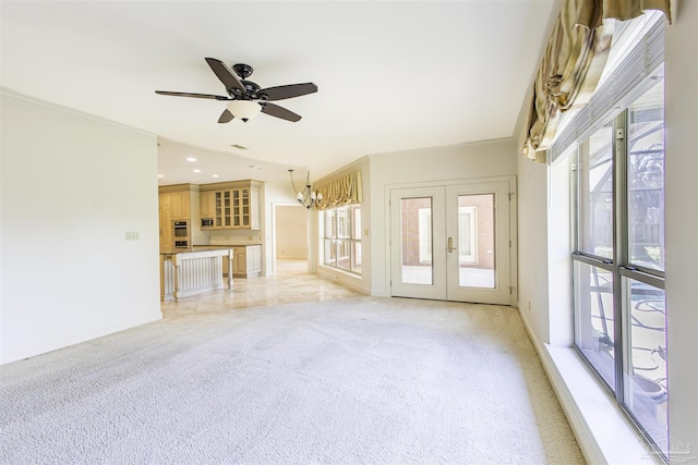 unfurnished living room featuring crown molding, plenty of natural light, light colored carpet, and french doors