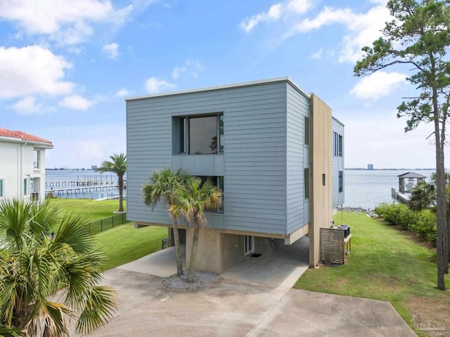 view of outdoor structure with a water view, cooling unit, and a lawn