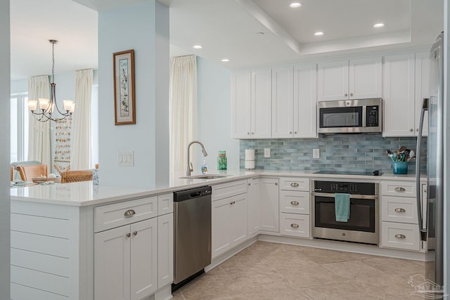 kitchen featuring stainless steel appliances, hanging light fixtures, sink, white cabinets, and kitchen peninsula