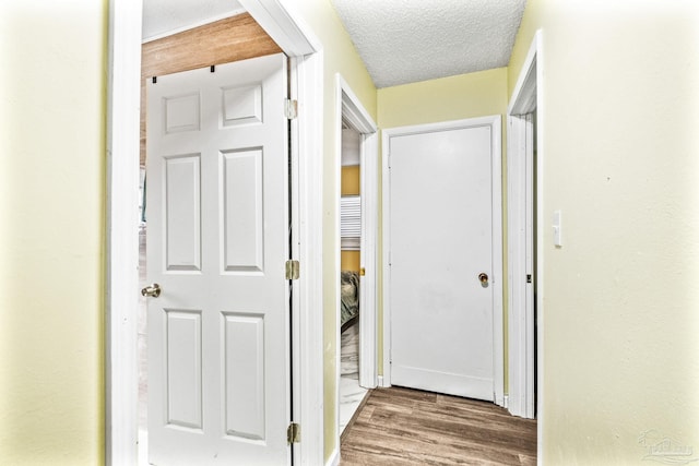 hallway with hardwood / wood-style flooring and a textured ceiling