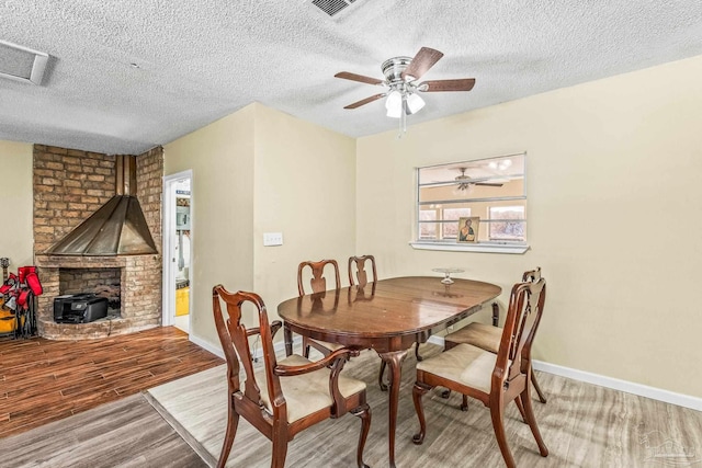 dining area with ceiling fan, light wood-type flooring, and a textured ceiling