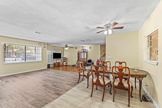 dining space featuring ceiling fan, light wood-type flooring, and a textured ceiling