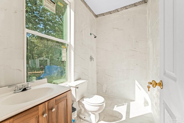 bathroom featuring a tile shower, vanity, and toilet