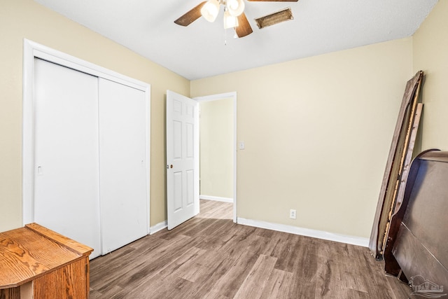 unfurnished bedroom featuring ceiling fan, a closet, and wood-type flooring