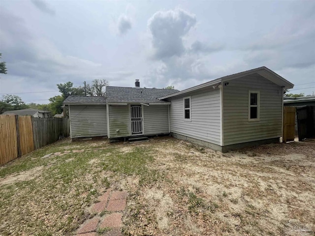 back of house with fence, a lawn, and roof with shingles