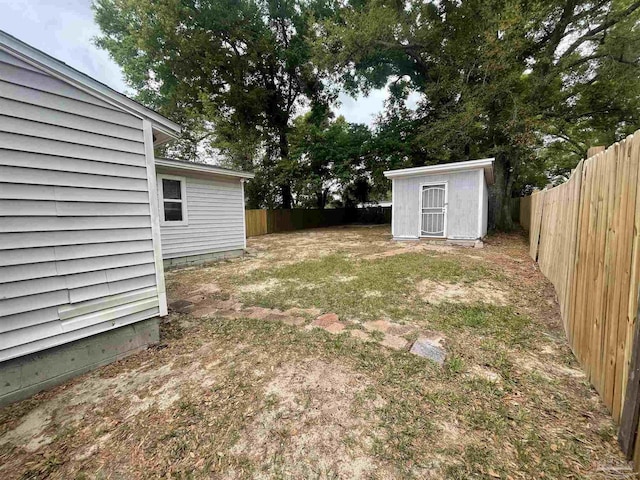 view of yard with a fenced backyard, an outbuilding, and a shed