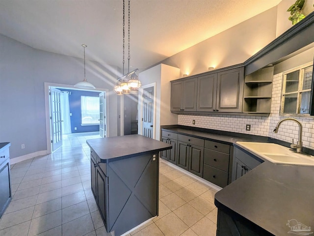 kitchen featuring sink, backsplash, vaulted ceiling, and a kitchen island