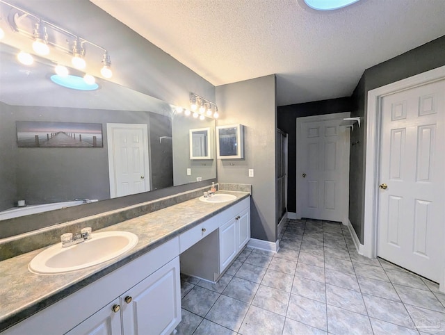 bathroom featuring double vanity, tile patterned flooring, and a textured ceiling