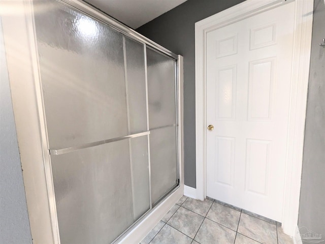 bathroom with tile patterned floors and a shower with door