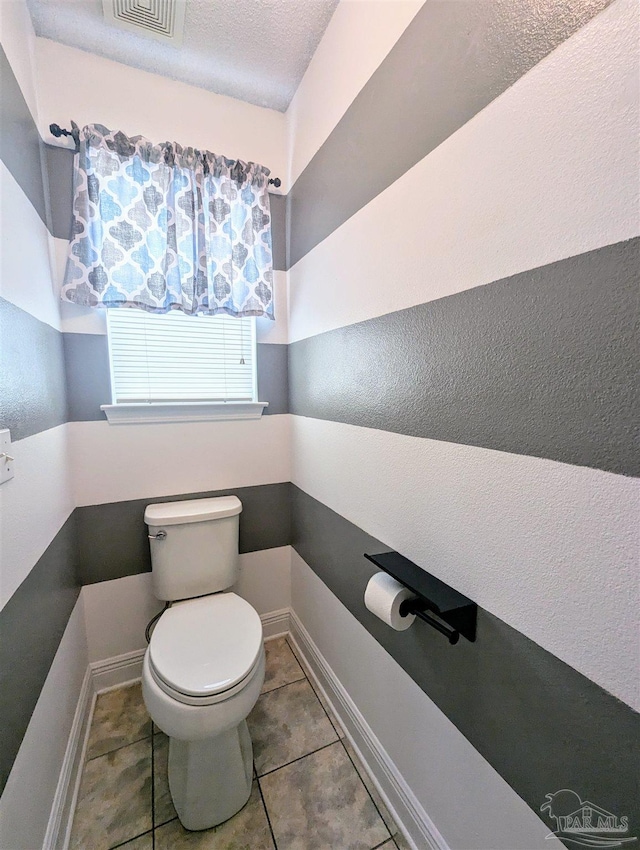 bathroom featuring tile patterned flooring, toilet, and a textured ceiling