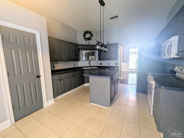 kitchen with white appliances, sink, a kitchen island, light tile patterned floors, and backsplash