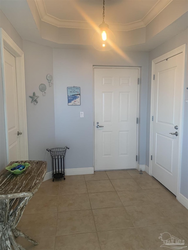 hall with crown molding, light tile patterned floors, and a tray ceiling