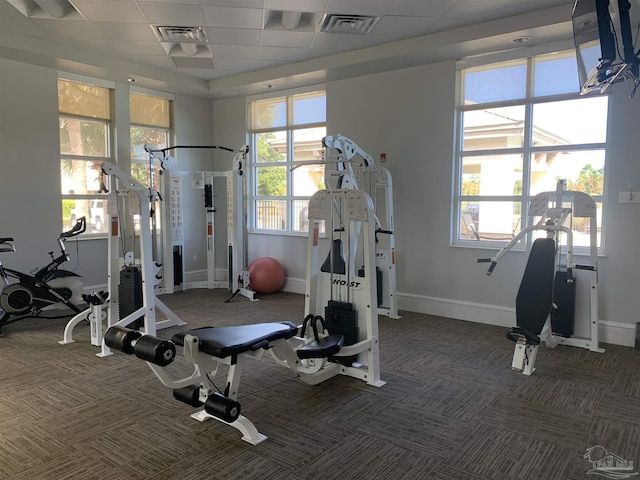 workout area with a wealth of natural light, a paneled ceiling, and dark colored carpet