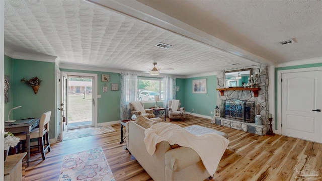 200 Talladega Trl, Pensacola, FL 32506 - living area with baseboards, a stone fireplace, light wood-style floors, crown molding, and a textured ceiling