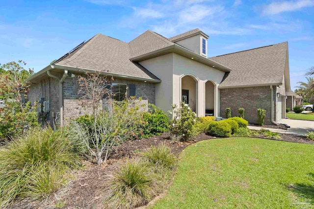 1397 Sabal Palm Dr, Gulf Breeze, FL 32563 - view of front of home with a shingled roof, brick siding, a garage, stucco siding, and a front yard