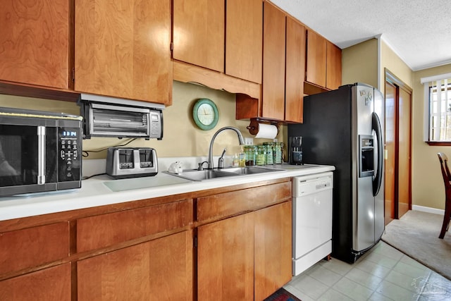 kitchen featuring light countertops, white dishwasher, a textured ceiling, and a sink