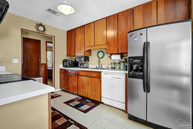 kitchen with brown cabinets, light countertops, visible vents, dishwasher, and stainless steel fridge with ice dispenser